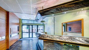 Un vestíbulo moderno con mostrador de recepción de mármol, paneles de madera y entrada de vidrio.