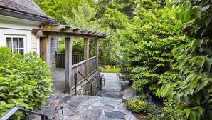 A stone pathway leading to a wooden pergola with a bench, surrounded by lush greenery. - Bedford Post Inn (Bedford)