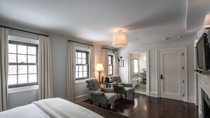 A hotel room with a large bed, two armchairs, a small table, a lamp, and a television. - Bedford Post Inn (Bedford)