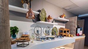En buffé med ett varierat utbud av mat, en kaffemaskin och en skylt som uppmärksammar ett projekt eller en organisation som arbetar med frågor relaterade till mat.