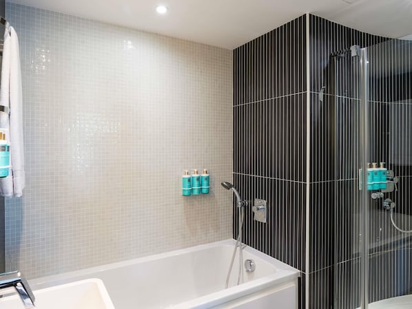 Une salle de bain moderne avec une baignoire, une douche et un mur recouvert de carreaux.