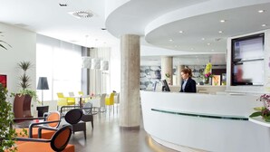A modern hotel lobby with a reception desk, seating area, and large windows. - Novotel Suites Malaga Centro (Málaga)
