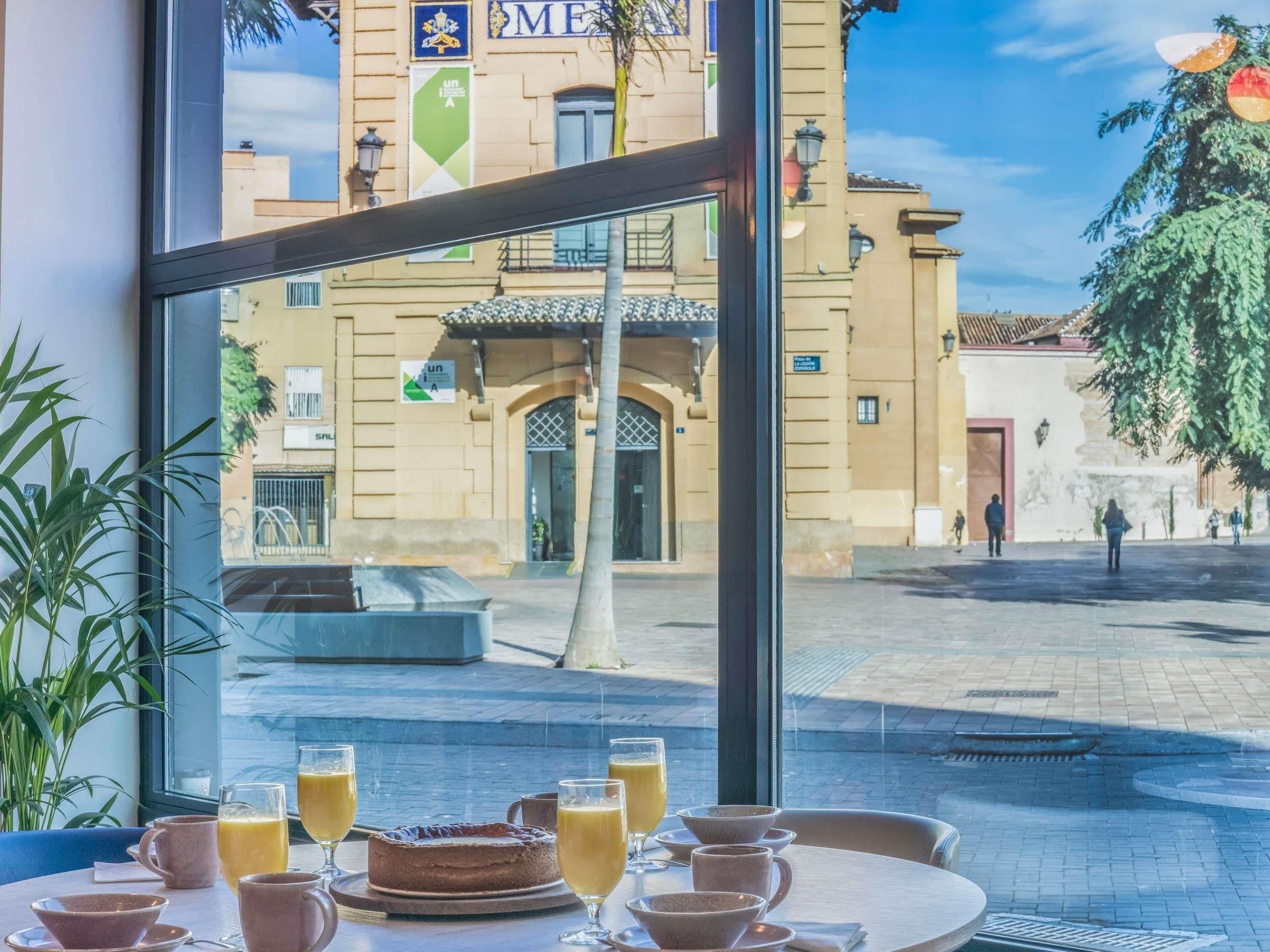 Ein Restaurant mit Blick auf ein historisches Gebäude, Außenbereich und einem Tisch mit Kuchen und Getränken.