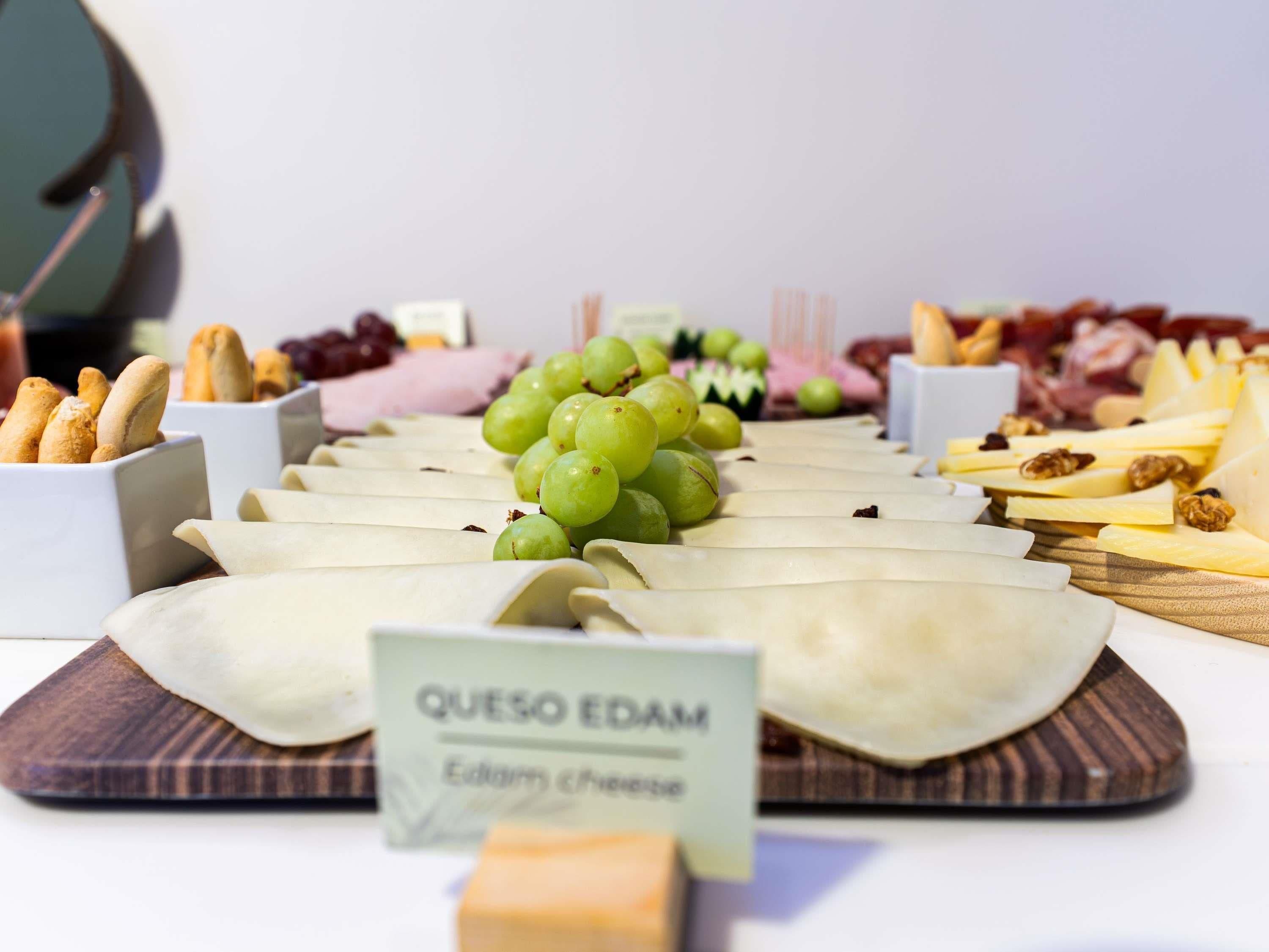 Un piatto di formaggio e frutta con un cartello che indica queso edam.