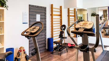 A gym with treadmills, a rowing machine, and weightlifting equipment.