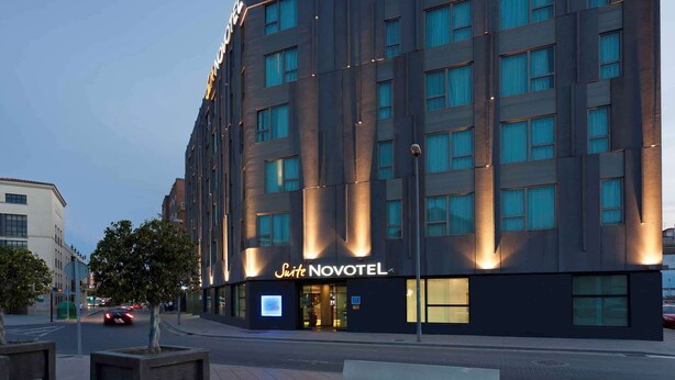 En modern hotellbyggnad med en mörk fasad och upplysta fönster.