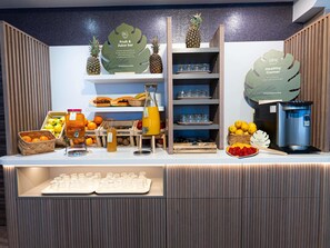 Un bar à jus avec des fruits frais, un distributeur d’eau et de la verrerie.