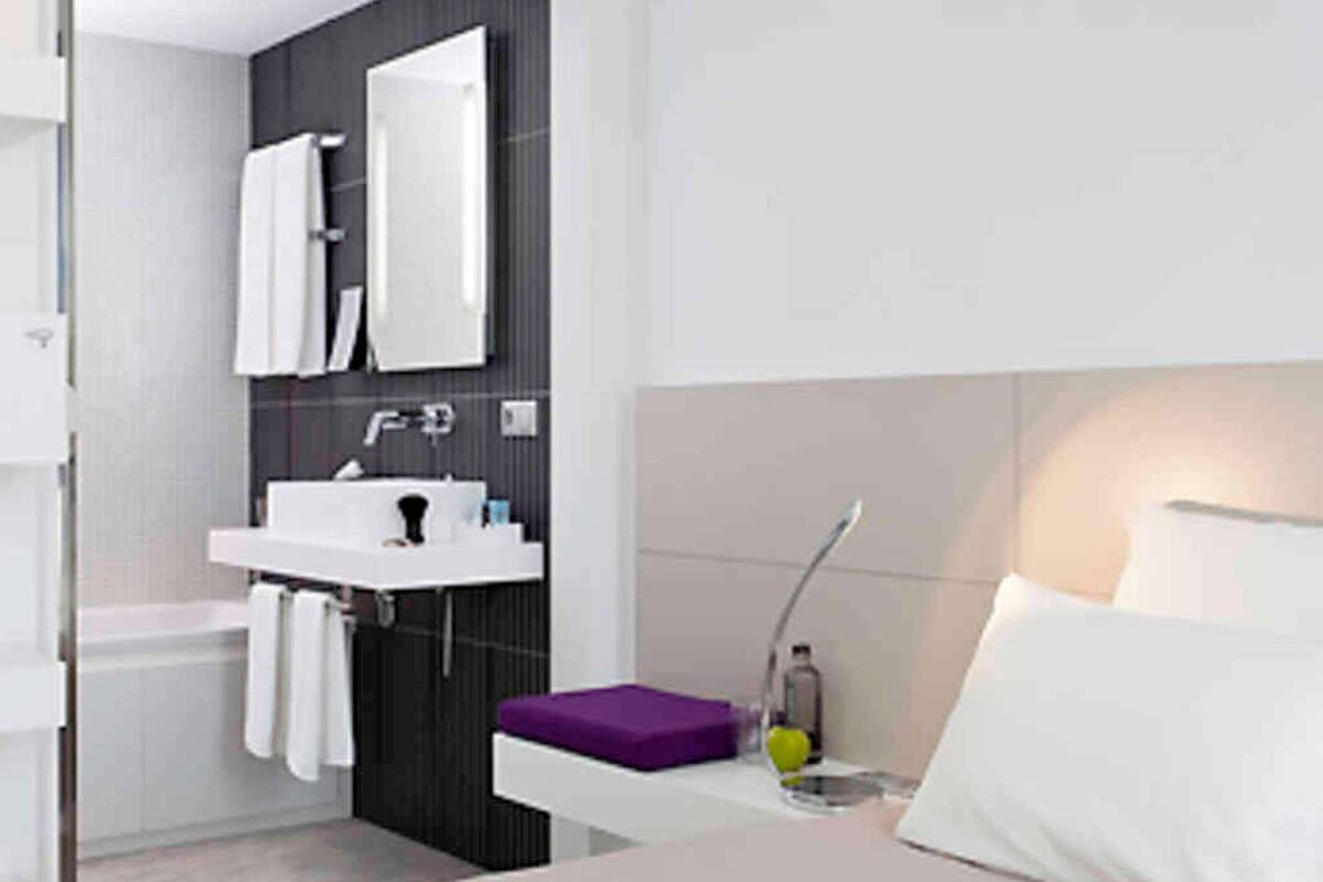 A modern bathroom with a white sink, mirror, and a purple towel holder.