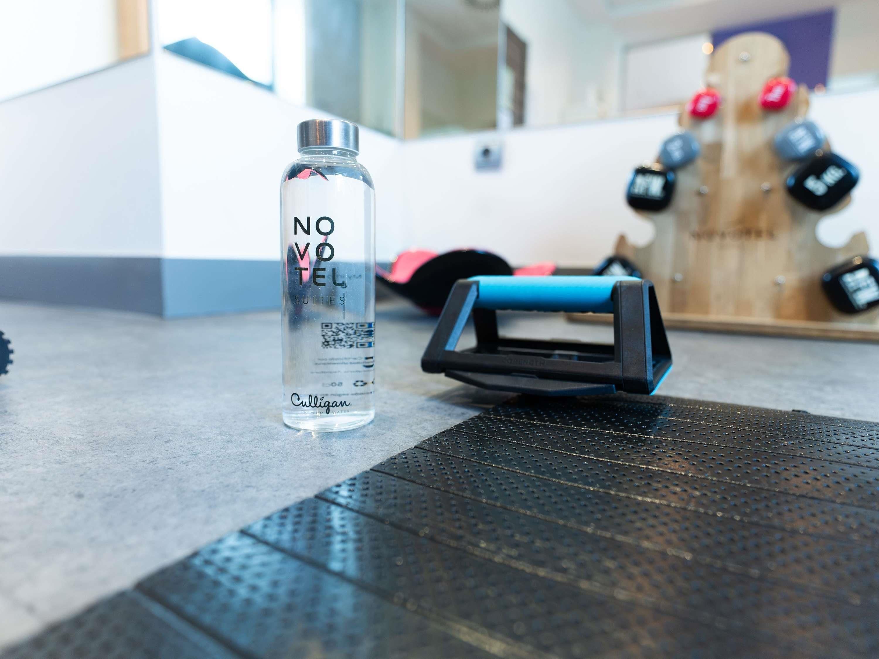 A clear water bottle labeled 'NO VOTE SUITES' and a blue and black exercise device on a textured mat.