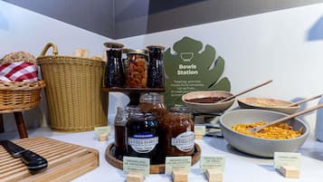 A breakfast station with jars of jam, bowls of cereal, and a sign indicating it's a Bowls Station.