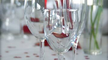 Una mesa servida con copas de vino, cubiertos y un florero con plantas verdes.