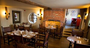Ein Restaurant mit Backsteinwänden, Holztischen und -stühlen.
