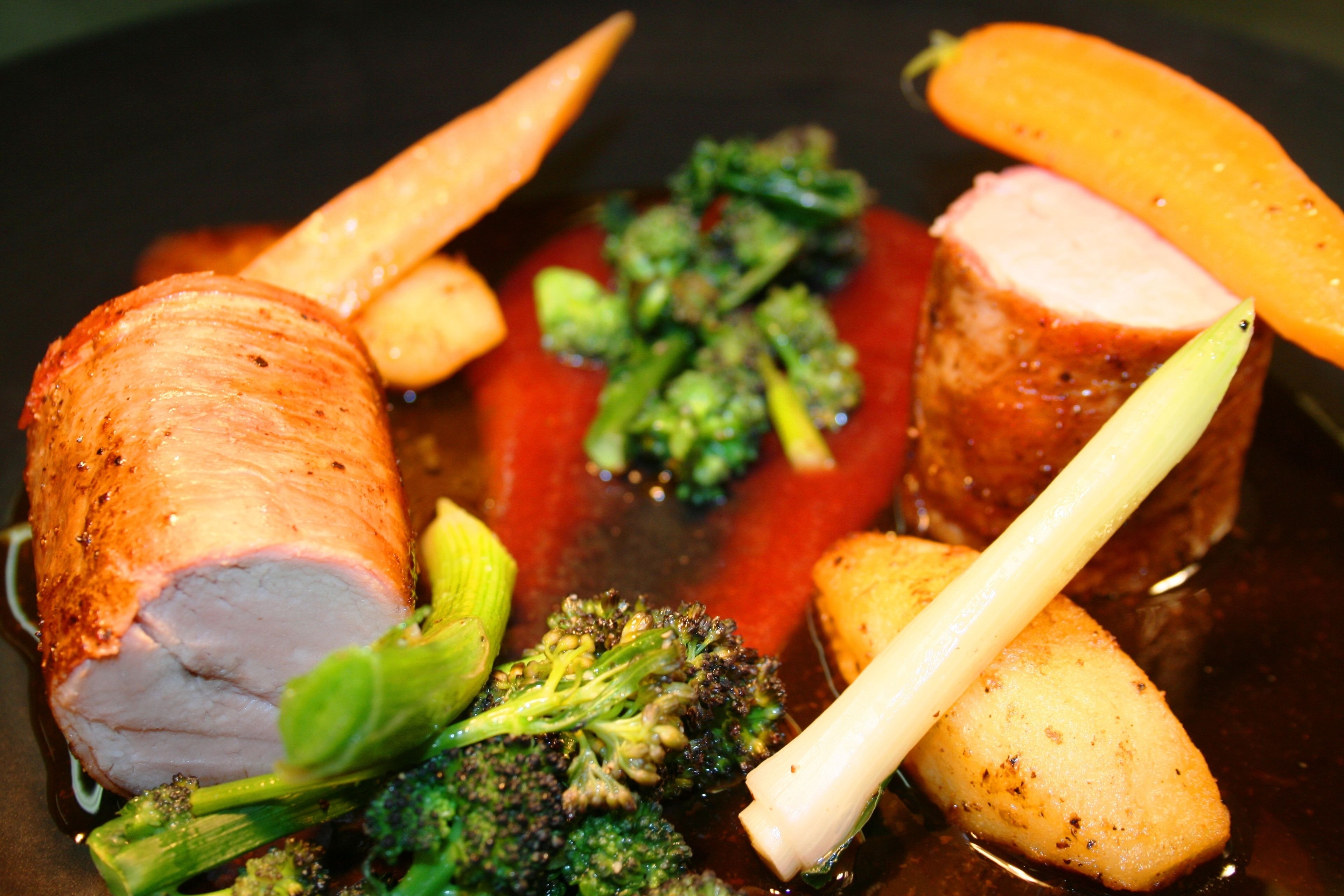 Un plato con carne de cerdo, brócoli, zanahorias y patatas.