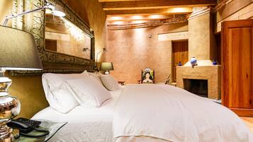 Habitación de hotel con cama, lámparas de noche, un espejo, chimenea y puerta de madera.