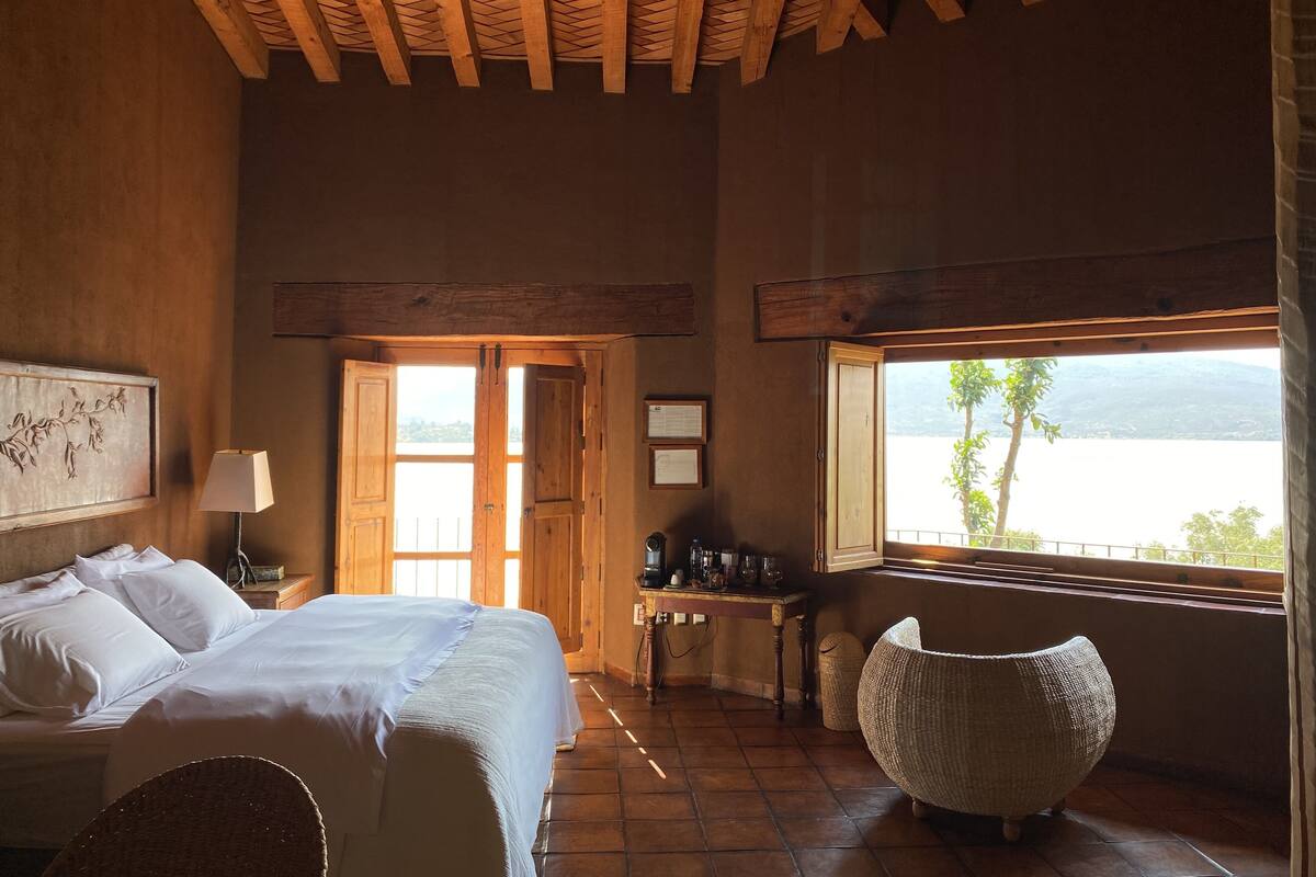 Une chambre à coucher avec un lit, un bureau, une chaise et une vue sur un lac.