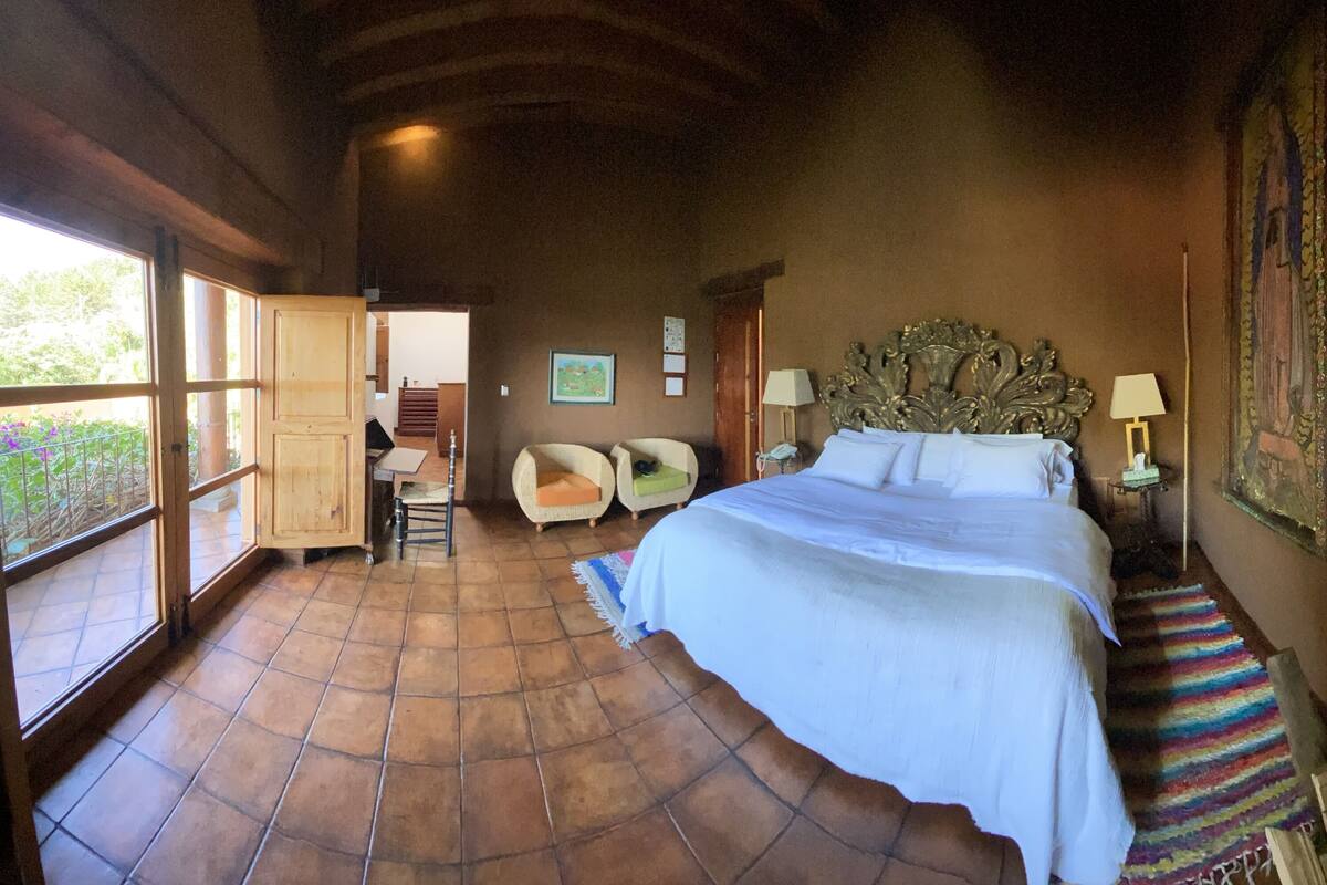 Une chambre avec un grand lit, une chaise, un bureau et une fenêtre.
