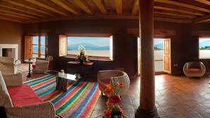 Ein Zimmer mit Bett, Sessel, Tisch und Blick auf die Landschaft.