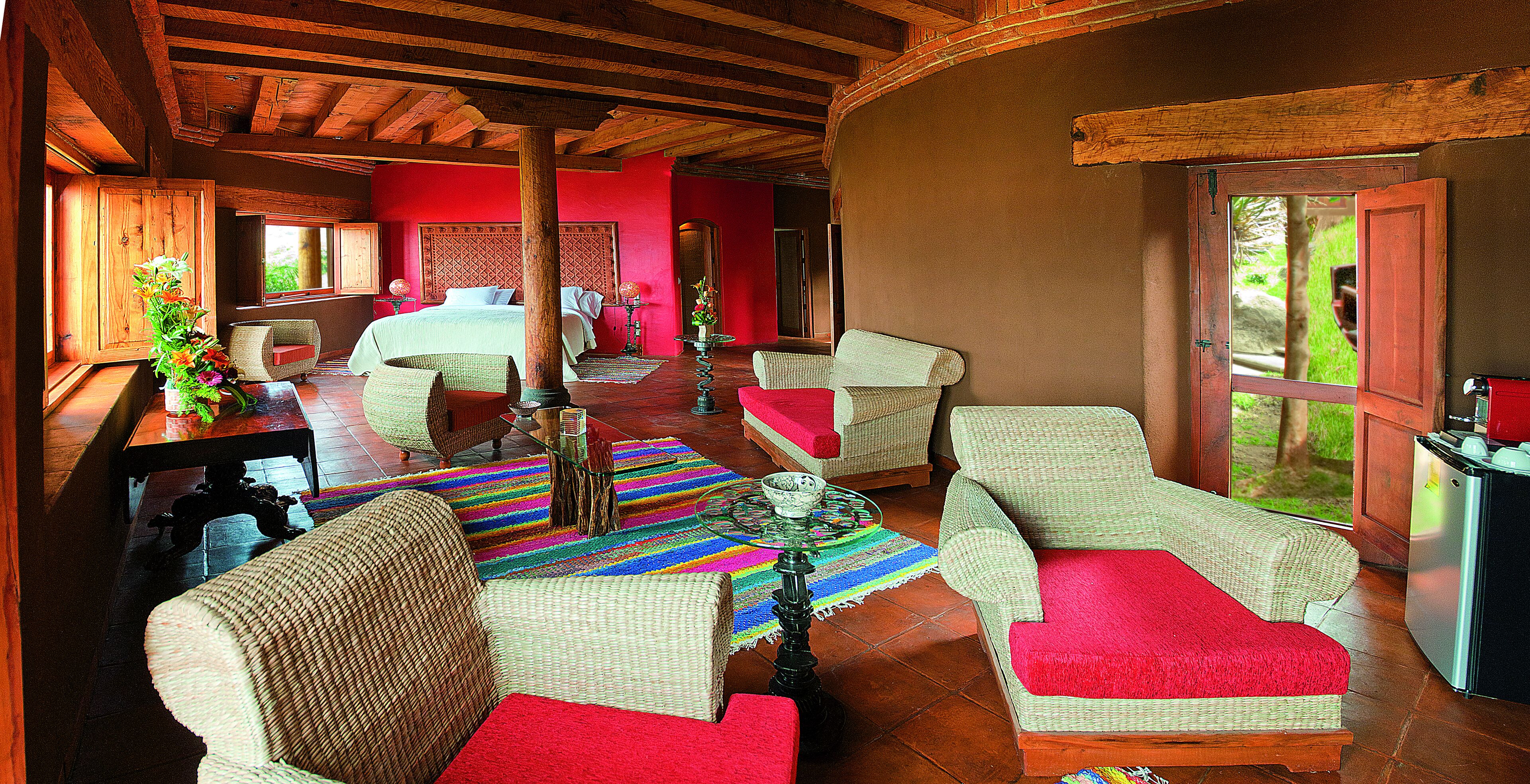 Una habitación amplia con una cama grande, muebles de mimbre y una alfombra colorida.