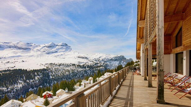 A wooden balcony with a view of snow-covered mountains and pine trees. - Dormio Resort Les Portes du Grand Massif (Araches-la-Frasse)