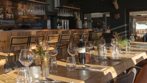 A restaurant with wooden tables set for dining, wine glasses, and bottles. - Dormio Resort Les Portes du Grand Massif (Araches-la-Frasse)