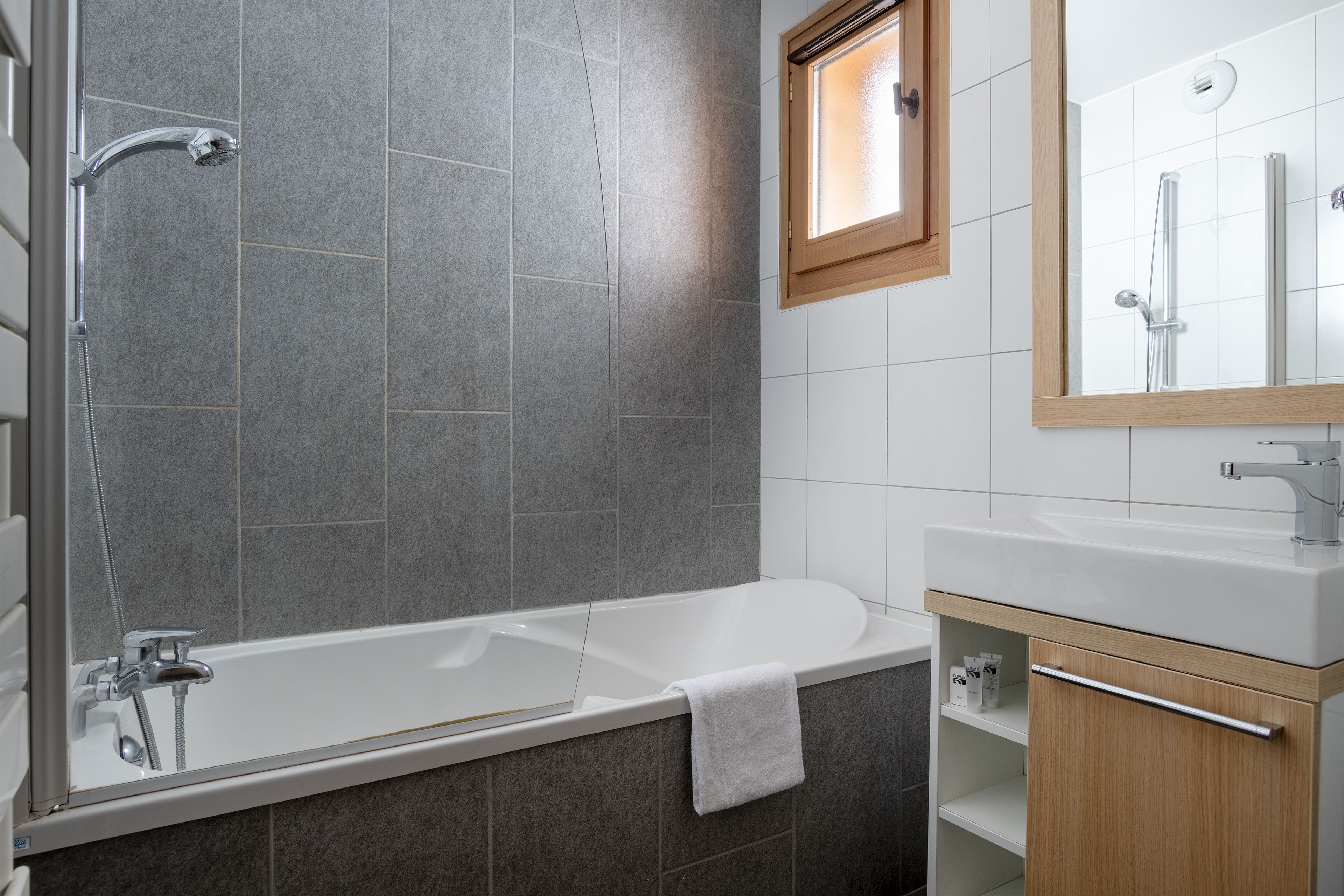 A modern bathroom with a bathtub, shower, and a vanity with a mirror.