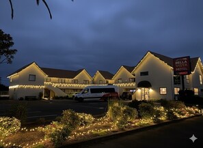 A motel with multiple buildings, a parking lot, and a van in front.