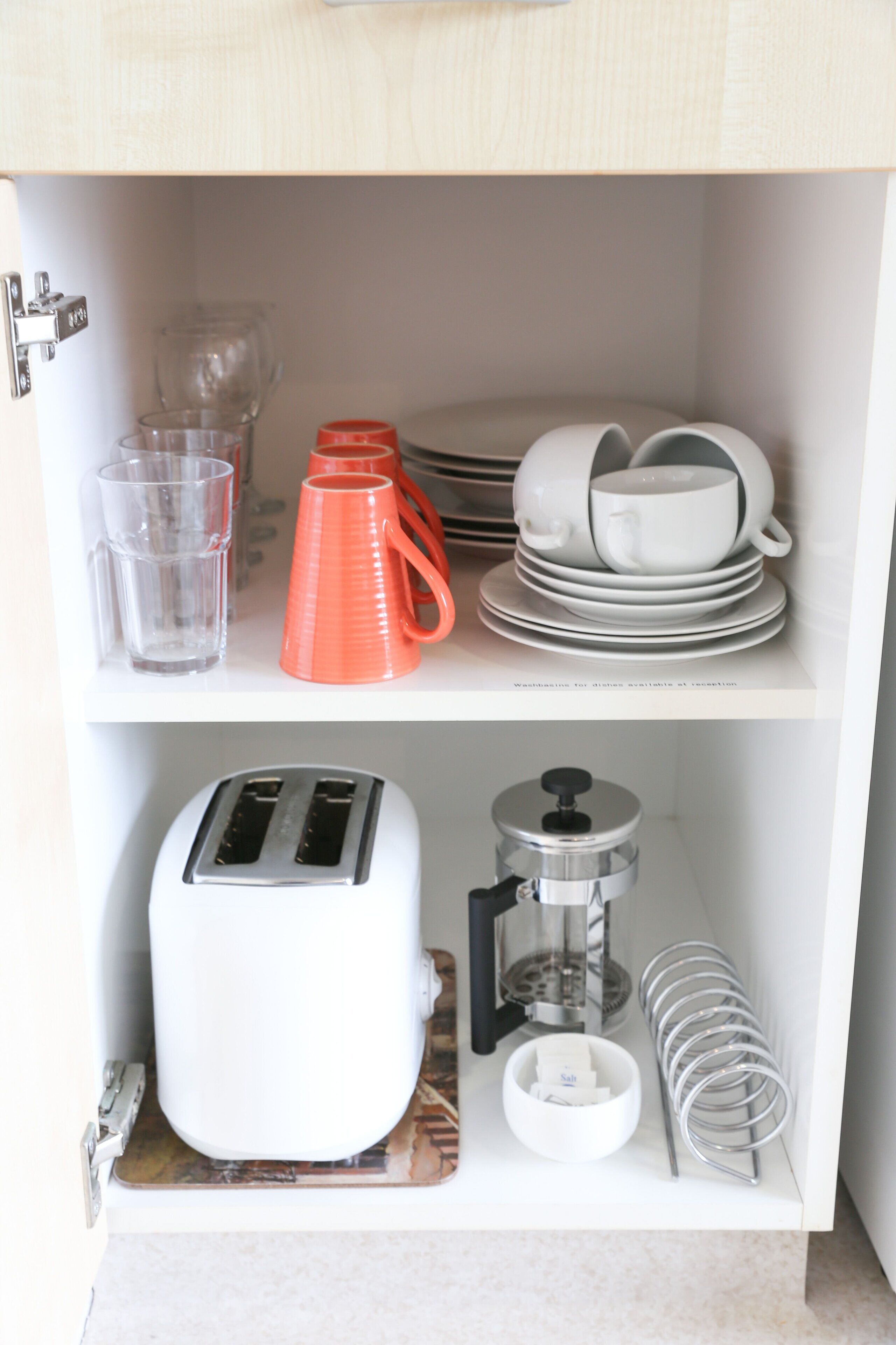 A kitchen with a toaster, a coffee maker, and stacked dishes on shelves.