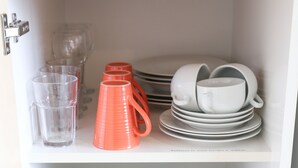 A kitchen with a toaster, a coffee maker, and stacked dishes on shelves.