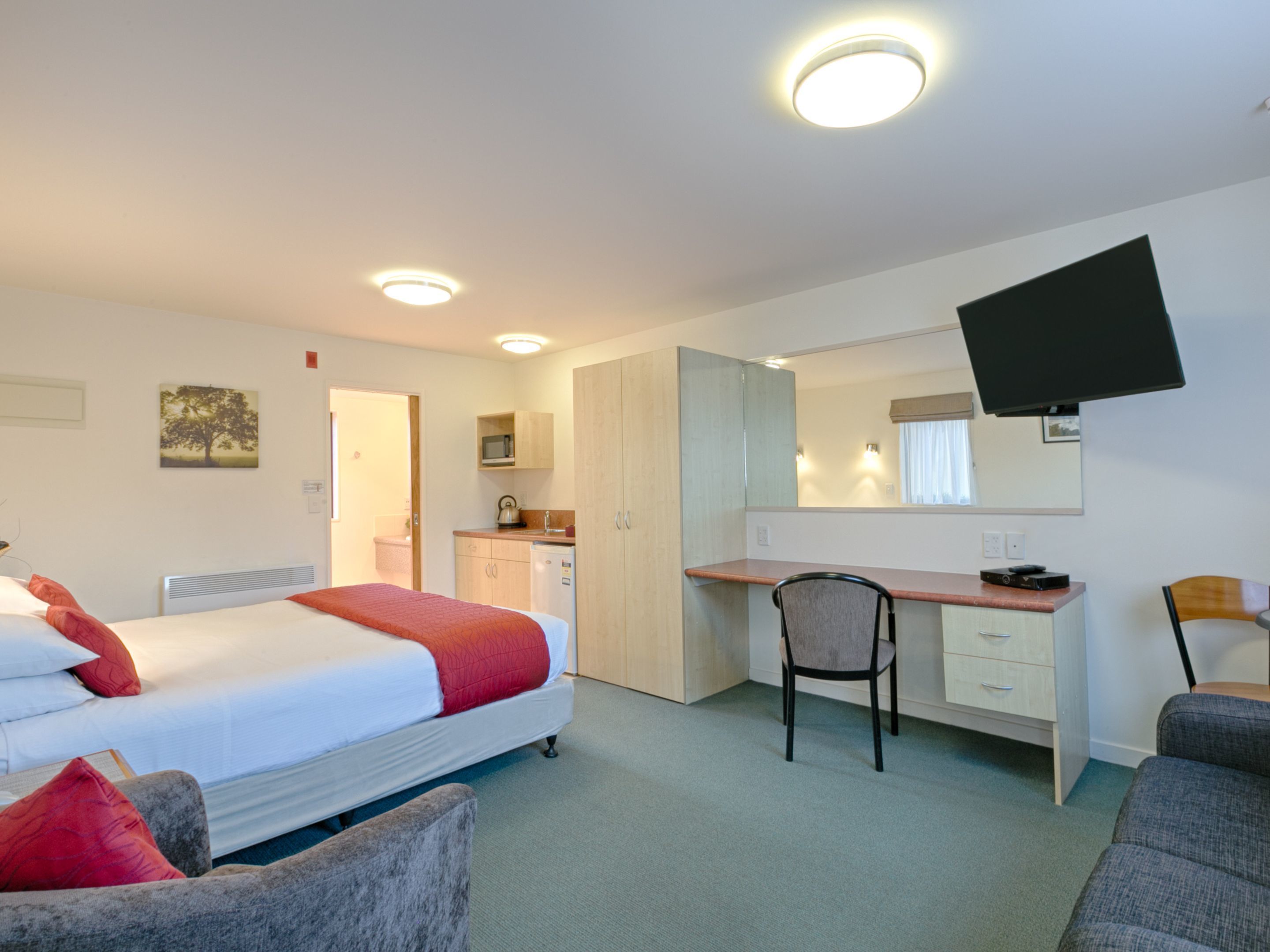 Een hotelkamer met een bed, bureau, stoel en kitchenette.