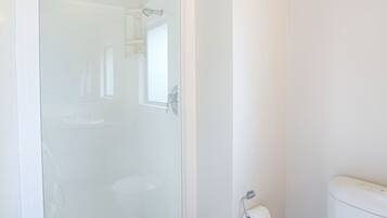 A bathroom with a glass-enclosed shower, a toilet, and a towel rack.