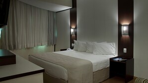 Una habitación de hotel moderna con una cama grande, mesitas de noche y un televisor montado en la pared.