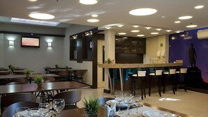 Un restaurante con varias mesas, sillas y una zona de bar.