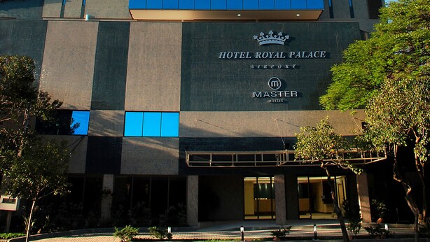Un hotel de diseño moderno, con una fachada de vidrio destacada y un letrero que dice "HOTEL ROYAL PALACE".
