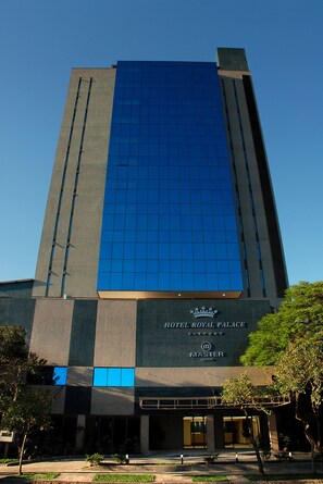 A hotel with a modern design, featuring a prominent glass facade and a sign that reads "HOTEL ROYAL PALACE".