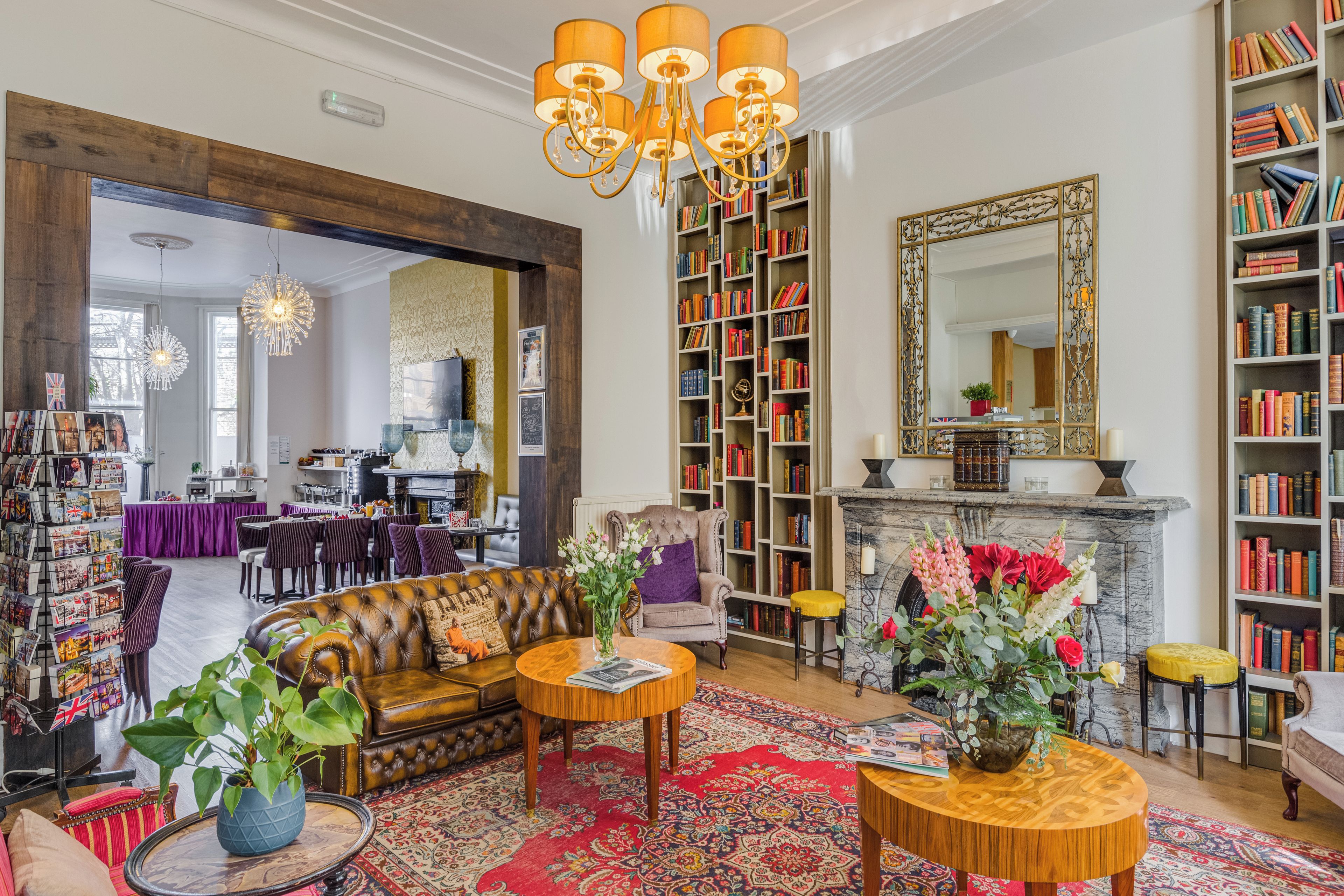 A spacious living room with a leather sofa, a fireplace, and a large bookshelf filled with books.