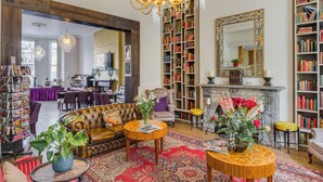 A spacious living room with a leather sofa, a fireplace, and a large bookshelf filled with books. - 1 Lexham Gardens (London)