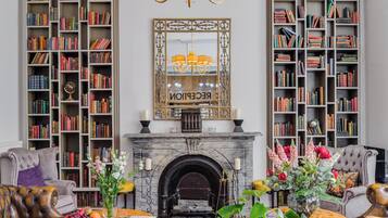 A library with bookshelves, a fireplace, and a chandelier.