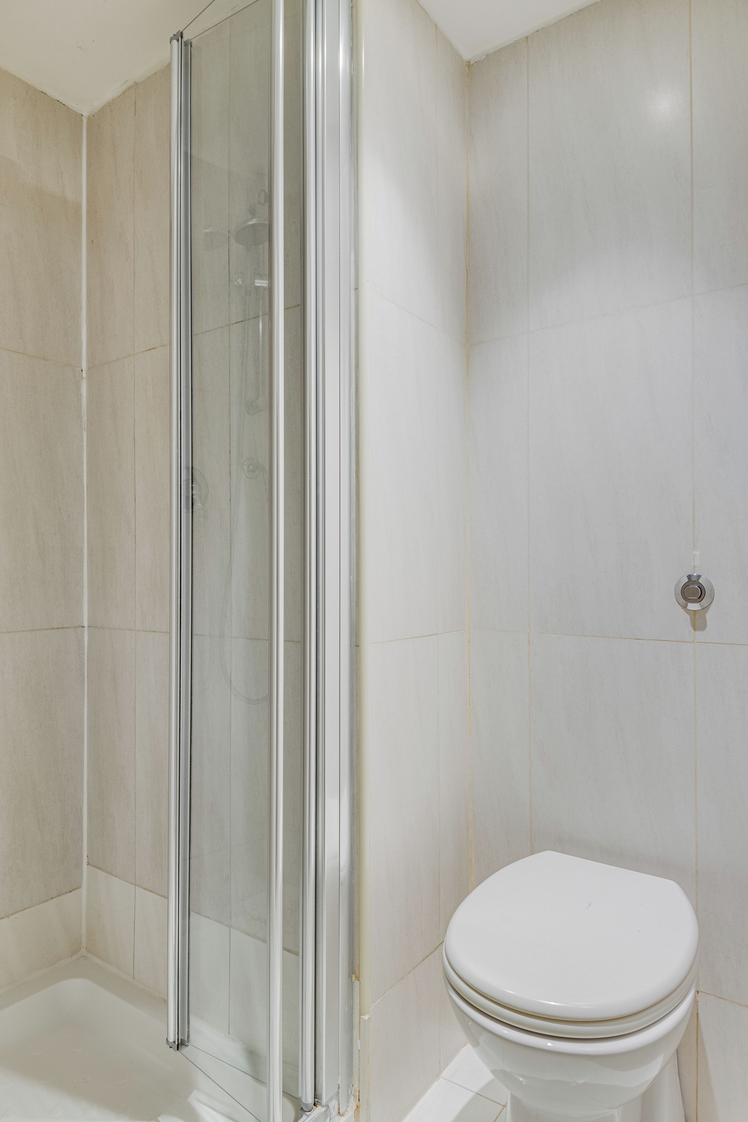 A bathroom with a glass shower enclosure, a white toilet, and tiled walls.