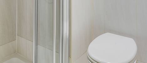 A bathroom with a glass shower enclosure, a white toilet, and tiled walls.