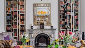 A library with bookshelves, a fireplace, and a chandelier. - 1 Lexham Gardens (London)