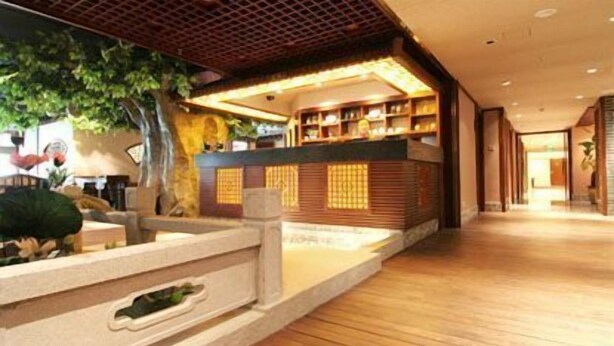 Un moderno vestíbulo de hotel con un mostrador de recepción de madera, una jardinera de piedra y vistas al interior.