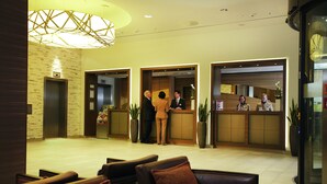 Zona de recepción de un hotel de diseño moderno, con mostrador de recepción, ascensores y área de descanso.