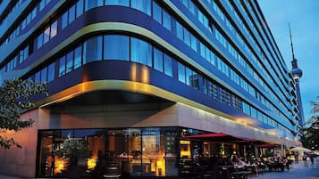 Ein modernes Hotel mit einer geschwungenen Fassade, großen Fenstern und einem Essbereich mit Außenplätzen.