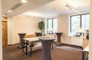 A modern conference room with a round table, two side tables, a potted plant, and large windows. - Hotel Berlin Alexanderplatz by Leonardo Hotels (Berlin)