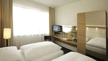 Una camera d'albergo con due letti, una televisione, una scrivania con il telefono e una finestra con tende.