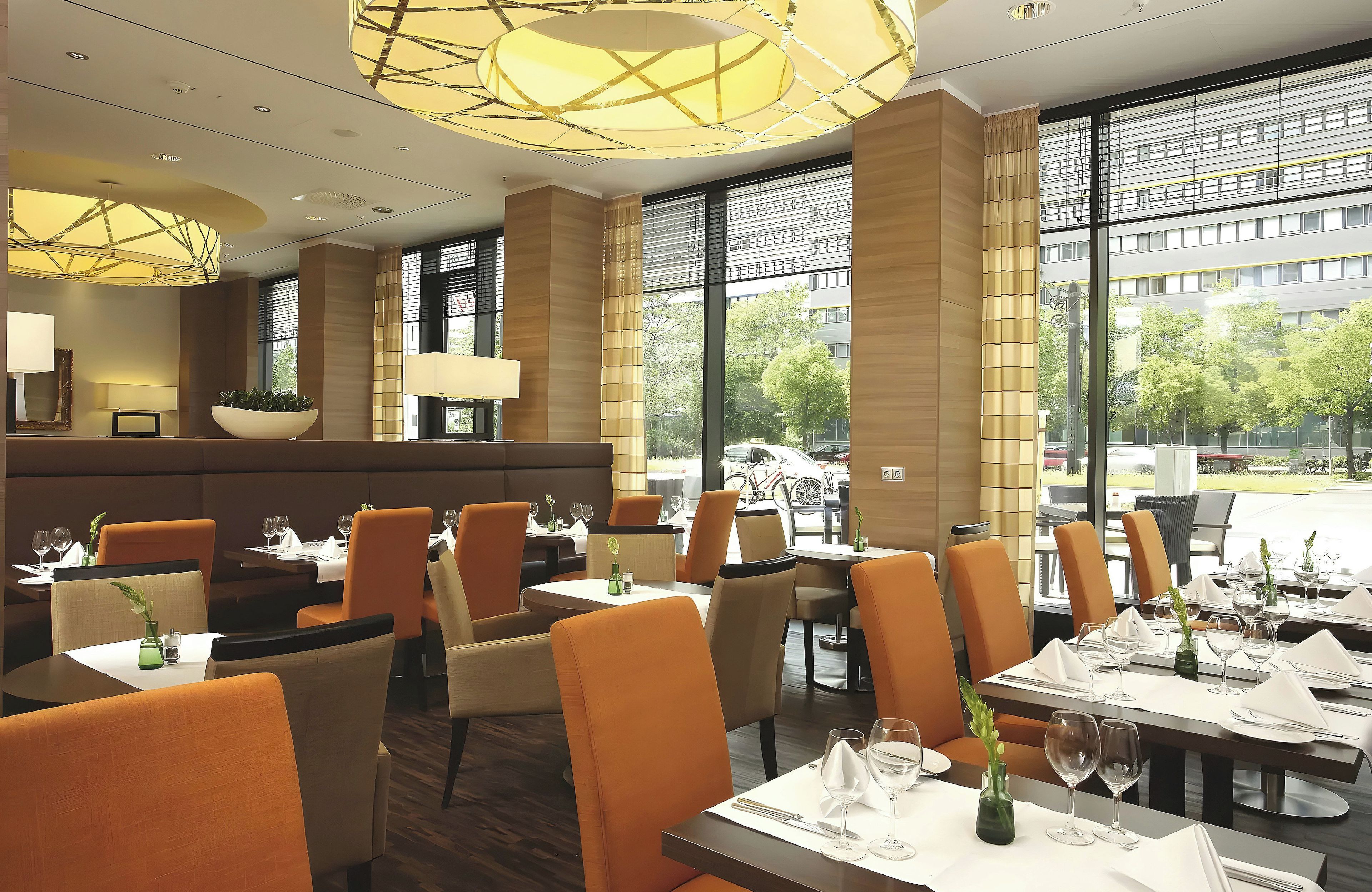 A restaurant with a modern interior, featuring a mix of seating options including tables and booths, and large windows offering a view of the outside.