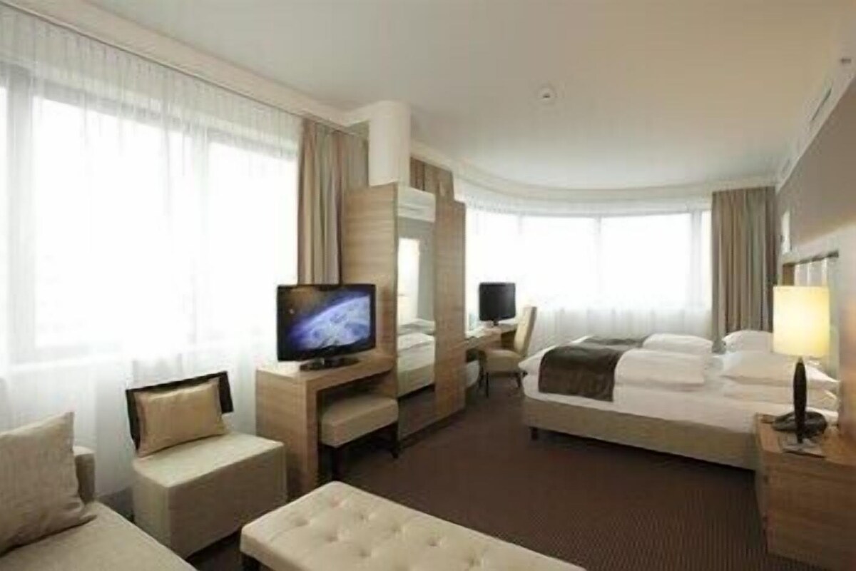 Una habitación de hotel con cama, televisión, escritorio y silla.