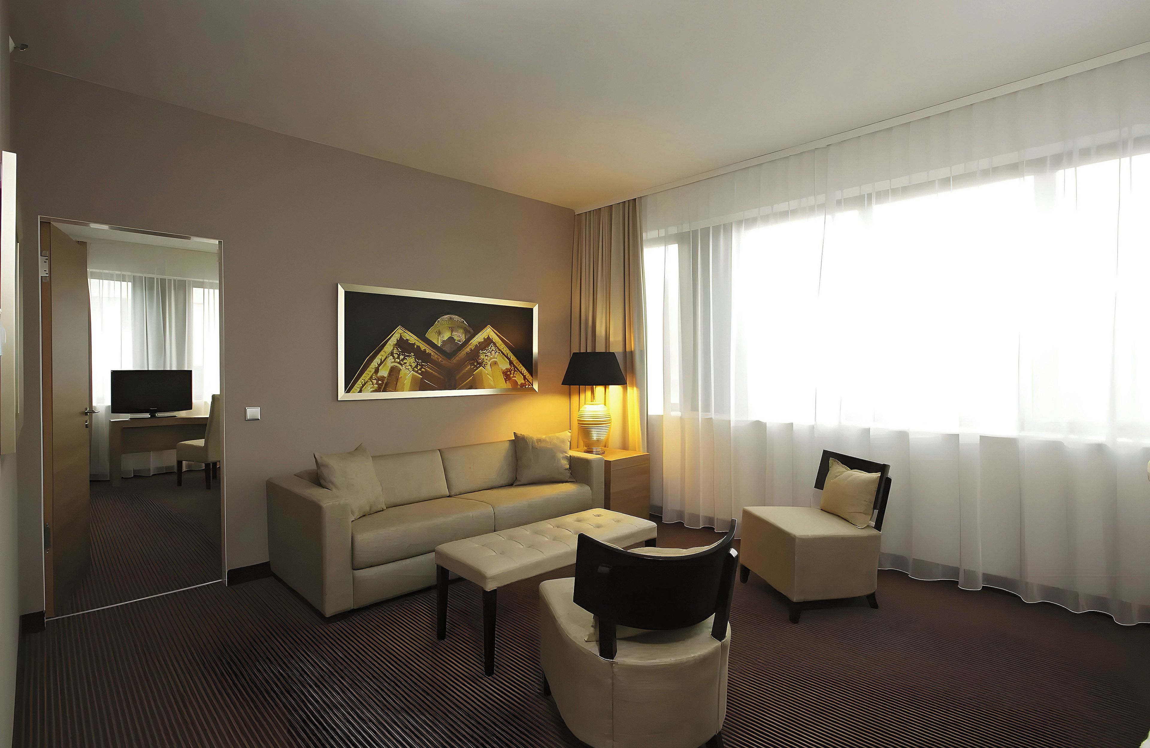 Ein Hotelzimmer mit Sofa, Sessel und Fernseher.