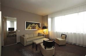 A hotel room with a sofa, armchair, and a television. - Hotel Berlin Alexanderplatz by Leonardo Hotels (Berlin)