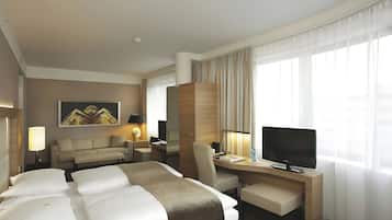 Ein Hotelzimmer mit einem Bett, einem Schreibtisch, einem Stuhl, einem Fernseher und einem Fenster mit Vorhängen.